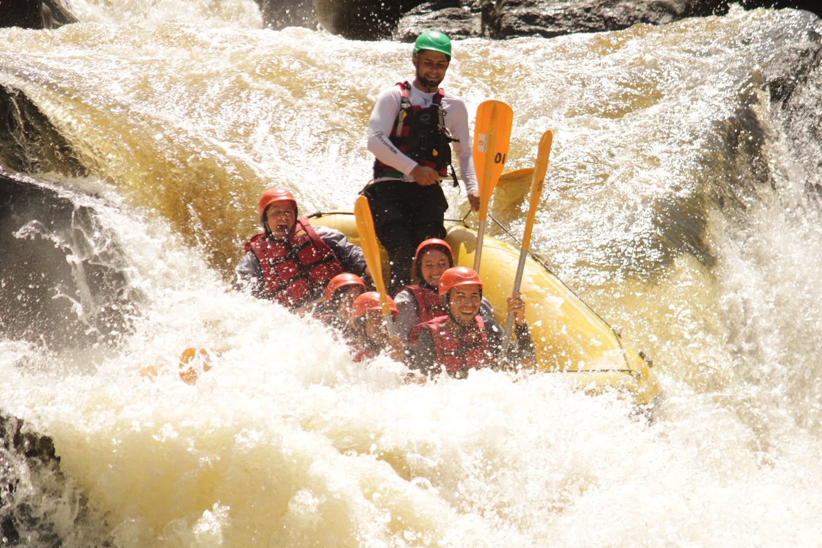Turma de capacete com os remos pro alto no meio da espuma de uma corredeira do Alto Braz