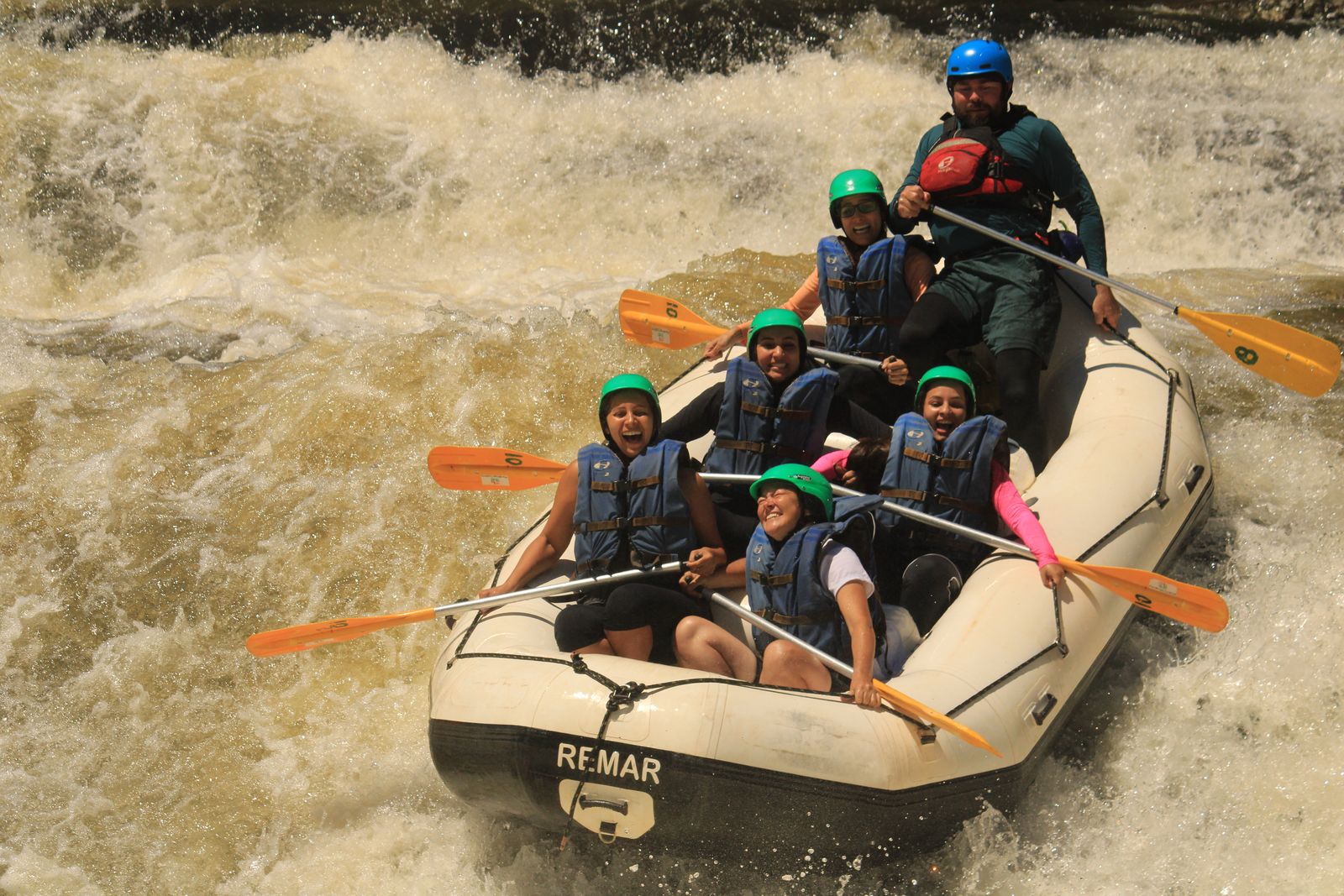 Turma sorrindo no bote enquanto desce uma corredeira forte no Santa Virgínia