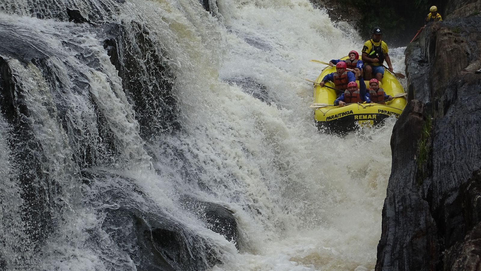 Bote despencando ao lado de uma cachoeira alta, entre paredões de pedra escura no Santa Virgínia