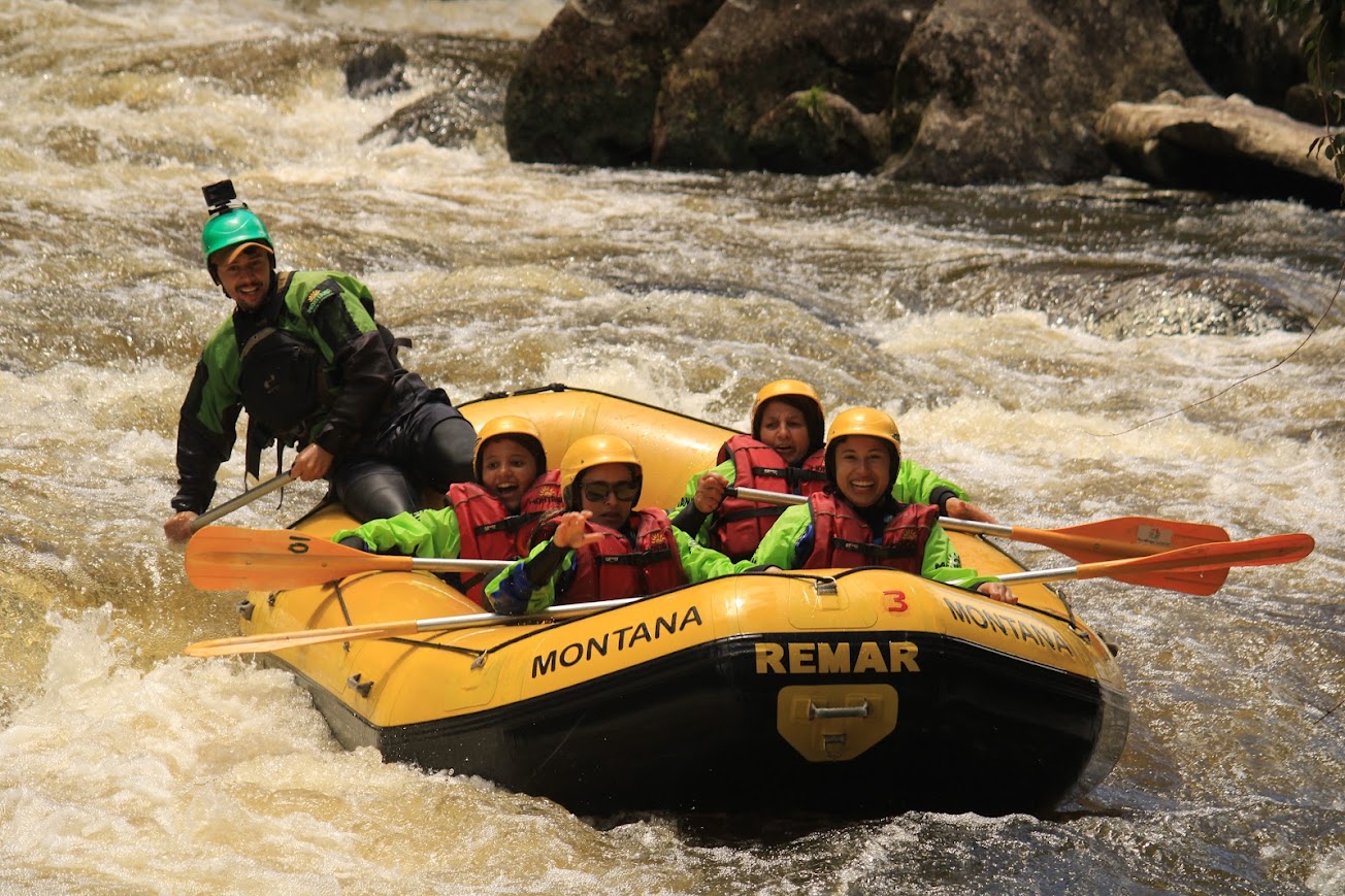 Instrutor e grupo rindo no bote em trecho de água agitada do Santa Virgínia
